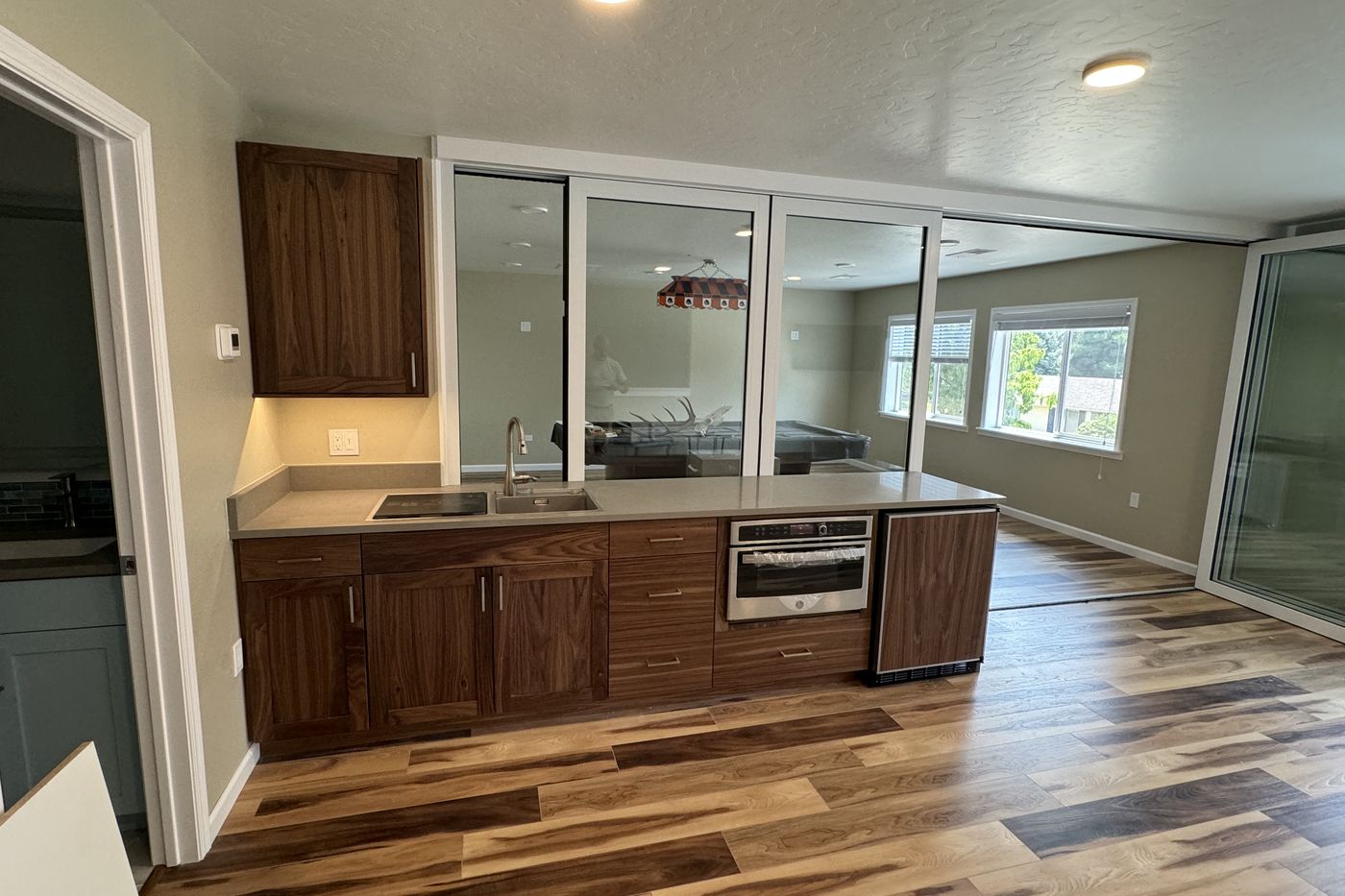 Lower level wet bar with walnut cabinets and a glass wall to a game room