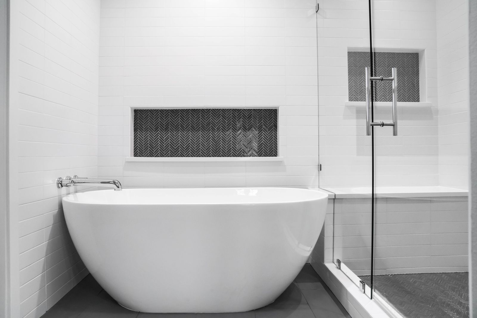 Remodeled bathroom with a freestanding tub and herringbone tile niche