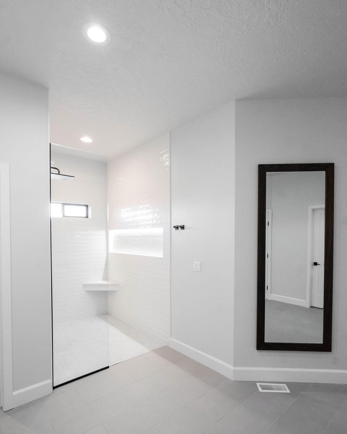 Bathroom remodel with a black-framed glass shower panel and a walnut-framed floor mirror