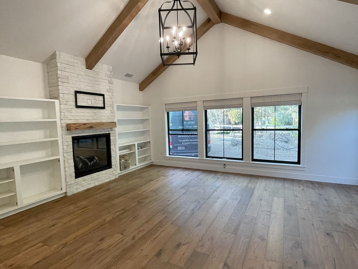 Vaulted ceiling framed with exposed oak beams over a fireplace and built-ins