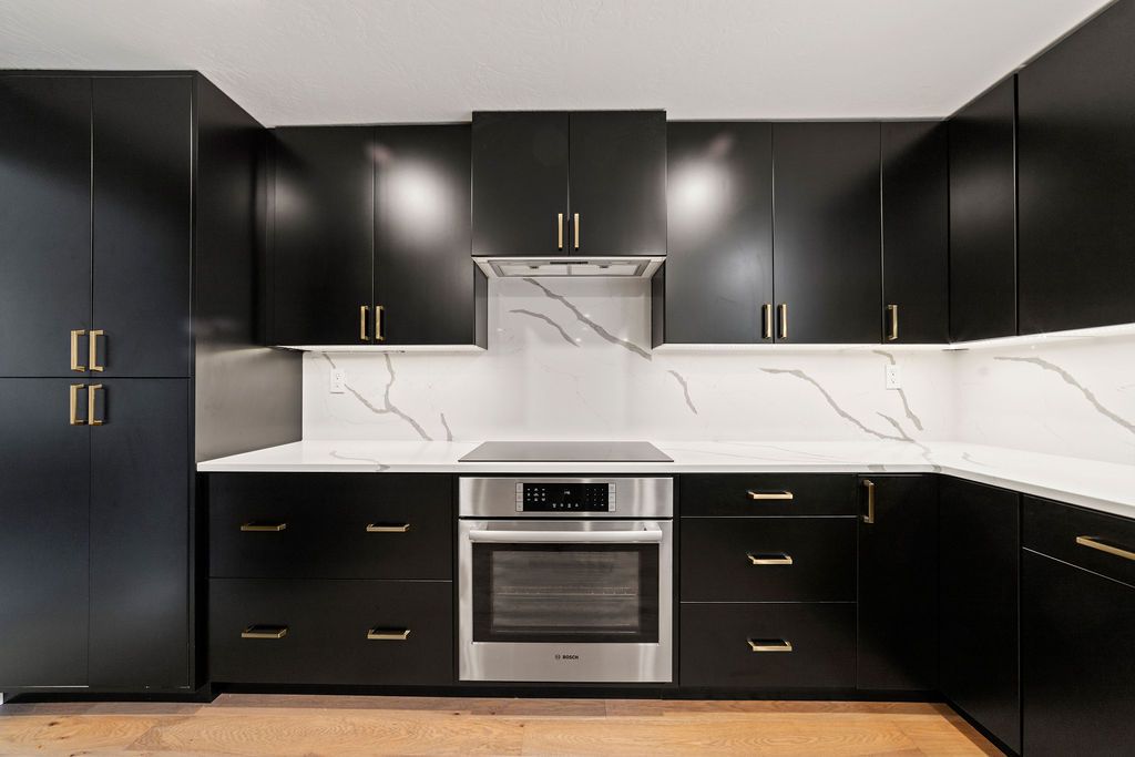 Custom black cabinets built around a wall oven and induction cooktop