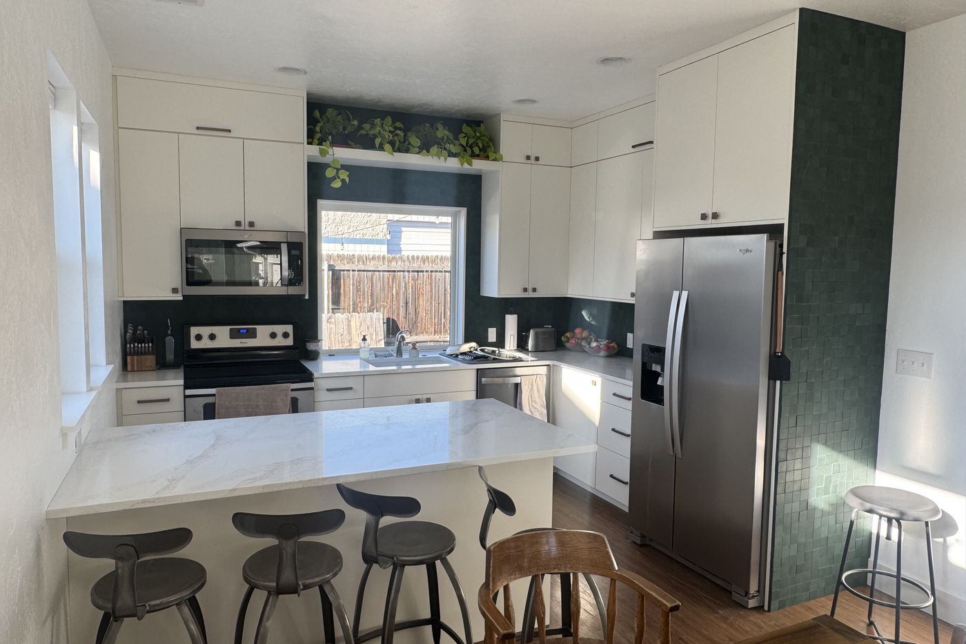 White kitchen with a green tile feature wall and new drywall
