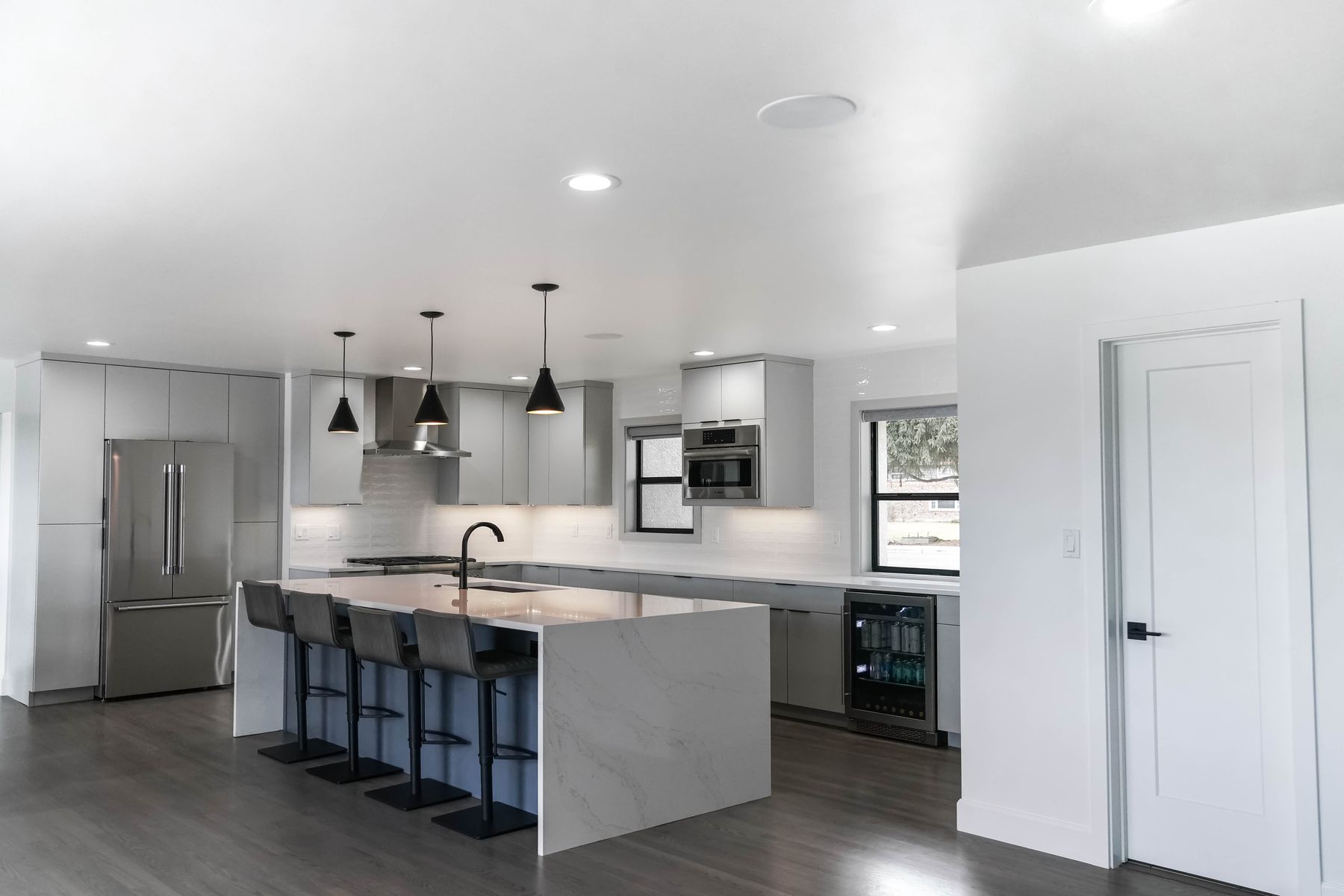Grey and white kitchen with a waterfall quartz island and black pendants