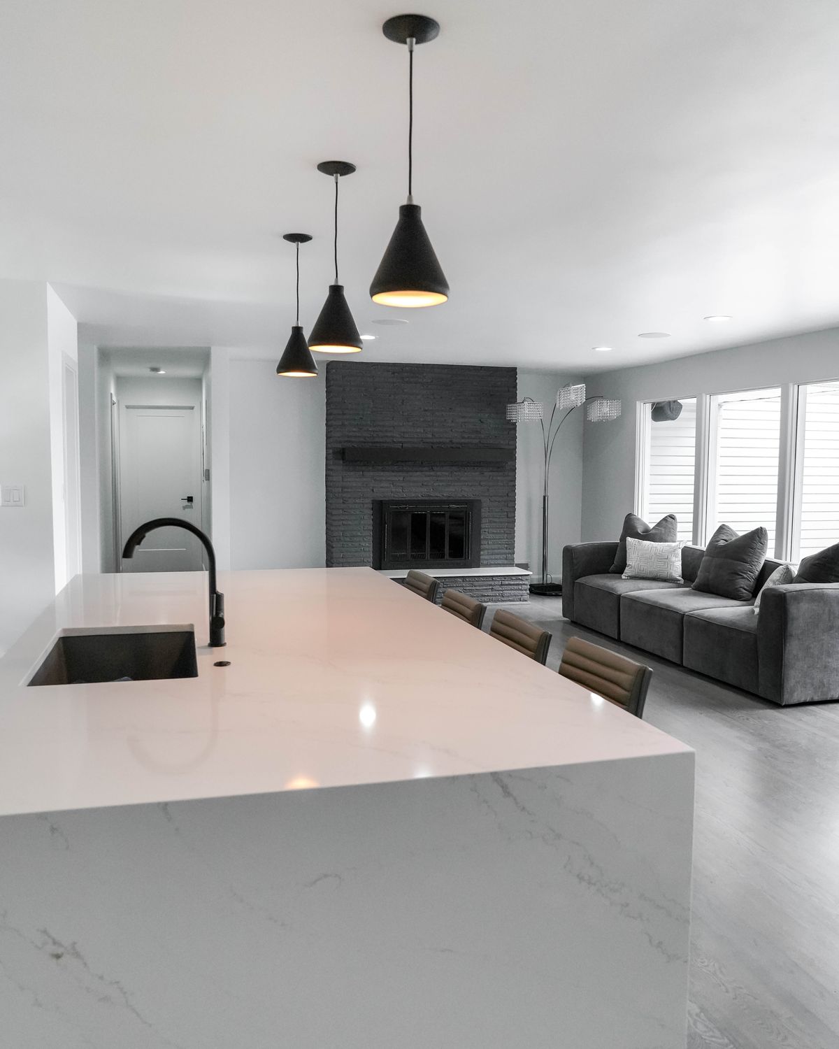 Remodeled kitchen opening onto a living room with a painted brick fireplace