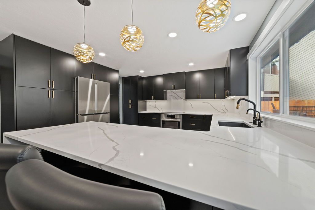 Quartz peninsula counter with gold pendants overhead