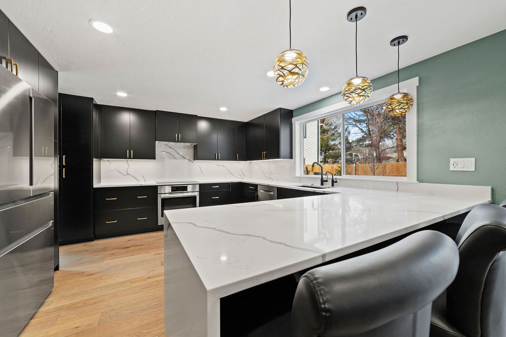 Sage green painted walls behind a quartz peninsula and gold pendants