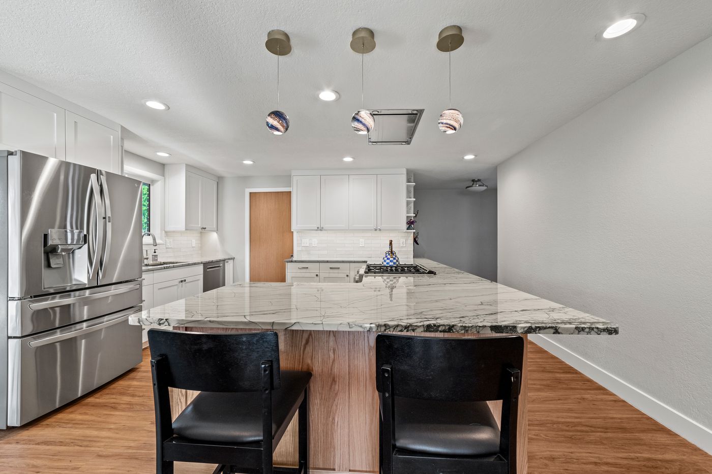 White shaker kitchen peninsula with two black bar stools