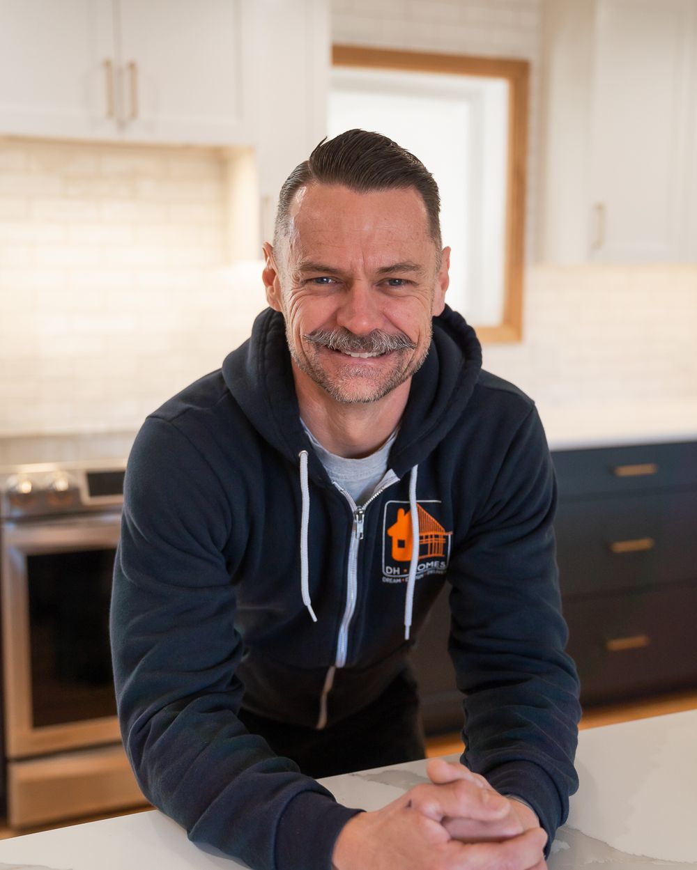 Chris Hapner of DH Homes standing at a kitchen island in a finished remodel