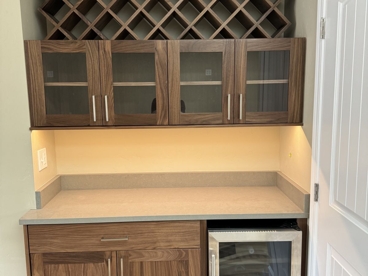 Built-in walnut wine nook with a diamond wine rack, glass-front uppers, and a wine fridge